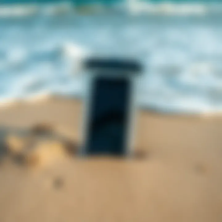 A mobile phone inside a transparent waterproof case placed on a sandy beach with waves in the background